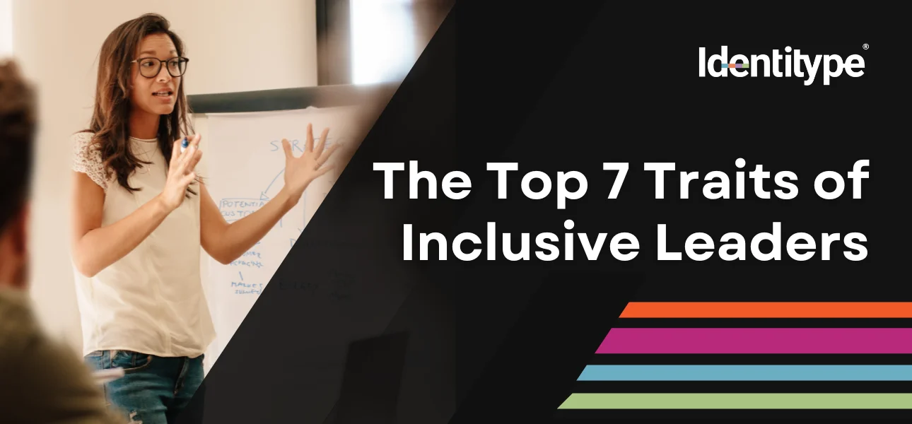 A woman in a casual white top and glasses is gesturing towards a flip chart during a presentation, with text on the right saying 'The Top 7 Traits of Inclusive Leaders' beside the Identitype® logo with a multicolored underline.