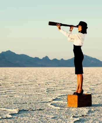 A person stands on a wooden box in the middle of a vast salt flat, peering through a telescope towards the horizon, symbolizing foresight and exploration.