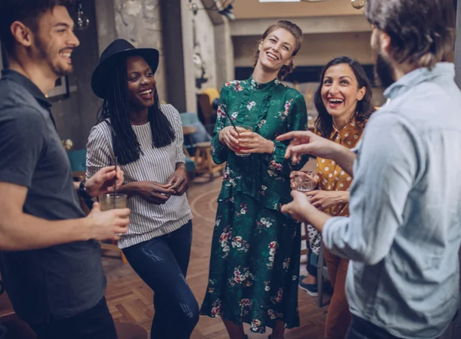 A lively group of individuals from diverse backgrounds laughing and enjoying a conversation in a casual, social setting.