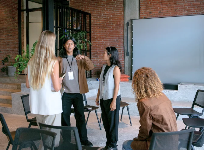 A group of professionals engaged in a team discussion in a modern office setting with brick walls and natural decor.